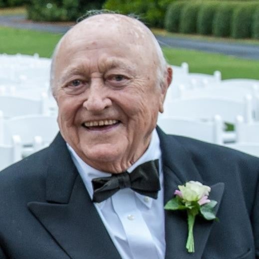 A man named William Russell Bridges is smiling while sitting down at a wedding